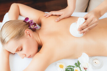 Obraz premium Hot herbal ball spa massage body treatment, masseur gently compresses herb bag on woman body. Tranquil and serenity of aromatherapy recreation in day lighting ambient at spa salon. Quiescent