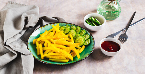 Appetizing French fries and cucumber slices on a plate on the table web banner