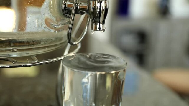 A beverage dispenser fills up a glass and then continues drip and overflow.