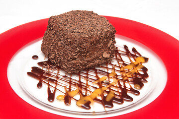 Chocolate cake topped with chocolate chips and mango and chocolate syrup, chocolate flake cake, dessert