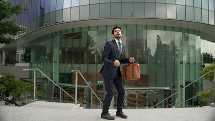 Professional business man dancing to celebrate successful while try to keep cool and keep looking. Skilled project manager wearing suit and bag while walking at building. Walking to office. Exultant.