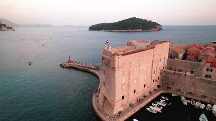 Aerial view of Dubrovnik fort by the sea, with boats and a stunning sunset creating a mesmerizing scene - Powered by Adobe