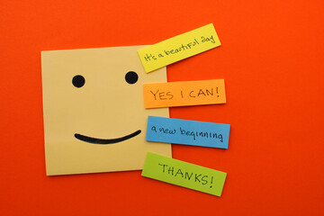 Happy face next to colorful notes with positive phrases