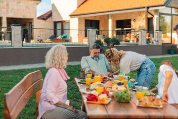 Family enjoying a rich lunch in the garden of their house