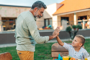 Grandfather and grandson giving high five at garden table