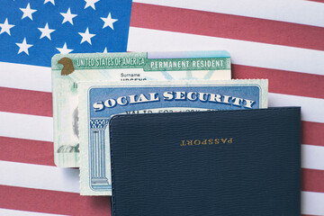 Passport, social security card and permanent resident (green) card on US flag. Immigration concept	