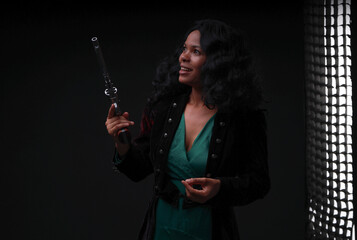 Young beautiful woman with curly hair holding old revolver low key portrait