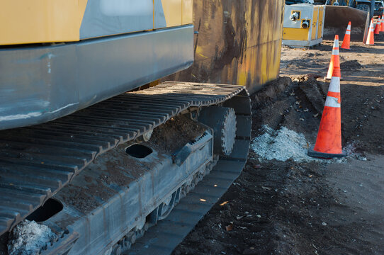 Heavy Construction Equipment at a Worksite with Traffic Cones. Close-up of heavy-duty tracked machinery on a construction site, with traffic cones in the background ensuring safety. Earthworks and ind