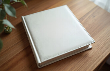 Fototapeta premium White leather wedding photo album with embossed cover lies on wooden table. Wedding book, album, leather, photo album, memories. Perfect for family photos, printing, archive, collection, publishing,