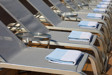 View of chaise lounge chairs with a folded towel on top with depth of field.