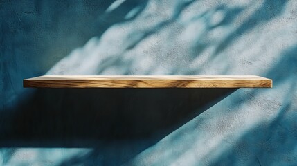 Wooden shelf against a textured blue wall with dappled light creating shadows and a minimalist aesthetic