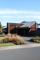 Fototapeta premium Modern architectural design of a residential home in a suburban neighborhood during clear daylight with a minimalist landscape