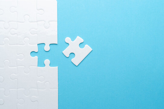 Concept for problem-solving, teamwork, solutions, or missing connections. White jigsaw puzzle on a vibrant blue background with one missing piece. Minimalist composition with copy space.