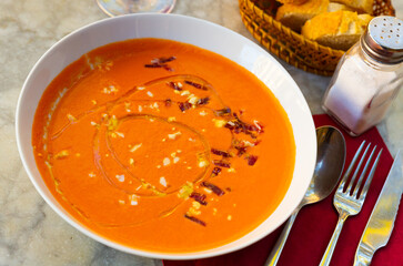 White ceramic bowl with salmorejo cordobes, typical spanish tomato soup similar to the gazpacho topped with serrano ham and croutons