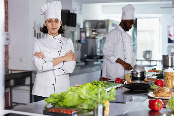 In a luxurious restaurant kitchen, female chef cooking tasty fine dining meals by preparing ingredients using stainless steel tools at the kitchen counter. Mastering food prep techniques.
