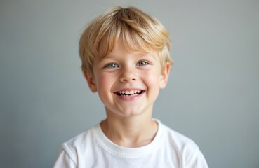 Cute blonde boy smiles widely with beautiful healthy teeth. Happy child demonstrates dental health, dentistry, positive emotions. Ideal for medicine, advertisement about teeth. Concept of perfect