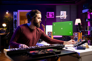 Sound producer learning new piano notes on midi controller, playing acoustic melody on electronic keyboard synthesizer with greenscreen on display. Singer watches tutorials to play music.