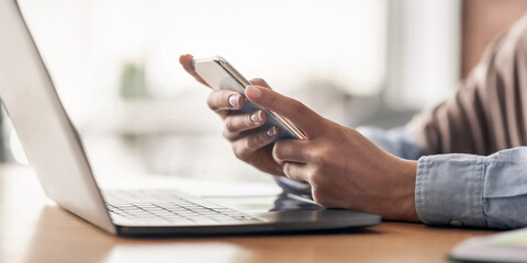 Female hands holding mobile phone and using laptop, freelancer working at cafe, cropped, copy space