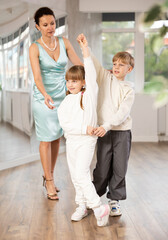 Small passionate ballroom enthusiasts, tween girl and boy practicing graceful waltz routine in...