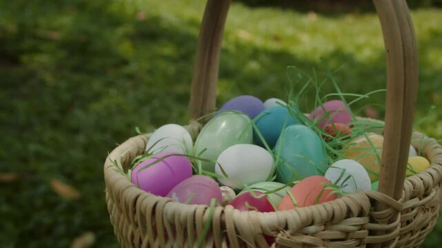 Basket with painted easter eggs, easter egg hunt game theme. Colored eggs in green grass to grab and collect, leisure game on holidays. The religious celebration of Easter.