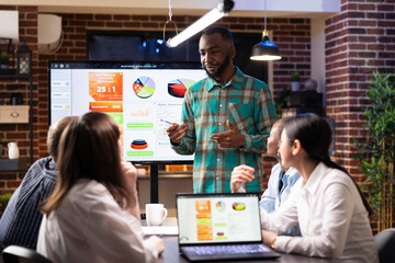 African american manager discussing with coworkers during late night meeting in brick wall...