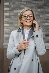 One mature woman outdoors in front of buildings talking on mobile phone, modern business and lifestyle concept