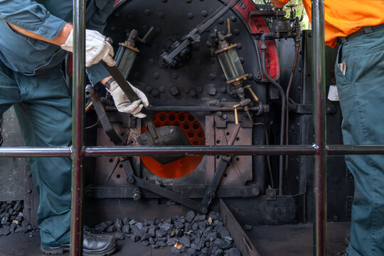 stoking steam train engine firebox fire with coal, vintage history rail railway locomotive,