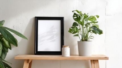 Fototapeta premium Black empty picture frame and houseplant. Hygge style decor