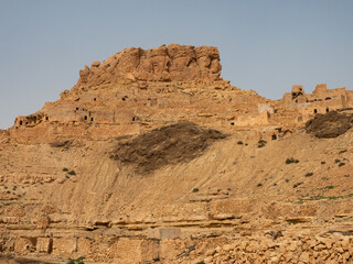 Fototapeta premium Ancient stone houses and on the mountain slopes in the Guermassa region. South Tunisia. Tatouine governorate. Tunisia