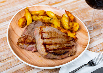 Grilled beef with fried potato served on table with serving pieces
