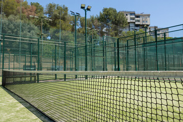 Fototapeta premium Empty outdoor padel tennis court with grass in daylight close up