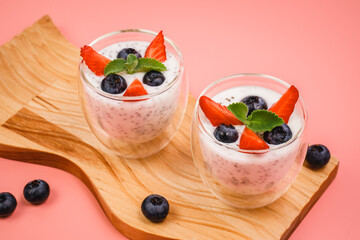 Healthy Chia Pudding in a Glass with Fresh Berries on Pink Background. Chia Pudding with Blueberries and Strawberries. 
Super food. Detox, diet, body cleansing