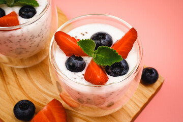 Healthy Chia Pudding in a Glass with Fresh Berries on Pink Background. Chia Pudding with Blueberries and Strawberries. 
Super food. Detox, diet, body cleansing