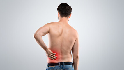 Back view of unrecognizable topless man touching his lower back zone highlighted with red,...