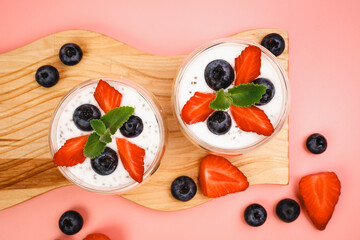 Healthy Chia Pudding in a Glass with Fresh Berries on Pink Background. Chia Pudding with Blueberries and Strawberries. 
Super food. Detox, diet, body cleansing