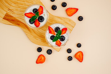 Healthy Chia Pudding in a Glass with Fresh Berries on Beige Background. Chia Pudding with Blueberries and Strawberries. 
Super food. Detox, diet, body cleansing