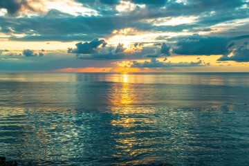 Fototapeta premium Breathtaking sunset over a tranquil ocean, casting vibrant colors across the sky and water.