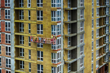 Fototapeta premium Worker insulates a high-rise building