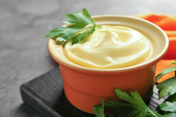 Delicious mayonnaise sauce in bowl with parsley on grey table, closeup