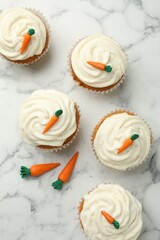 Delicious carrot cupcakes on white marble table, flat lay