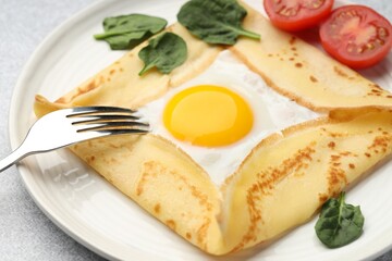 Delicious crepe with egg, tomato and basil on table, closeup