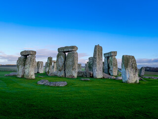 Naklejka premium Stonehenge A large group of stone structures are surrounded by a lush green field