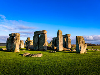 A large group of stone structures are surrounded by a lush green field