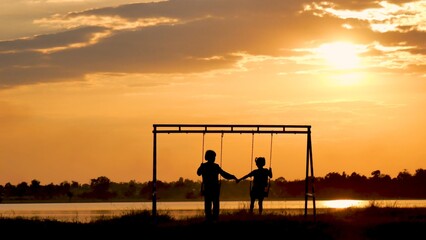 Silhouette two girls sitting on swing playing at playground together friendship concepts. Girls...