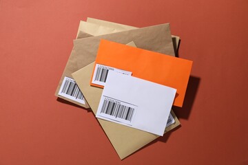 Different paper envelopes on red-brown background, top view. Post office