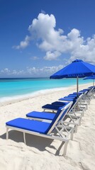 Turquoise ocean water meets white sands, while blue beach chairs align under the sunny blue sky
