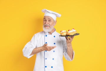 Professional pastry chef with delicious profiteroles on orange background
