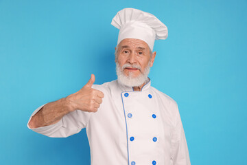 Professional pastry chef showing thumbs up on light blue background