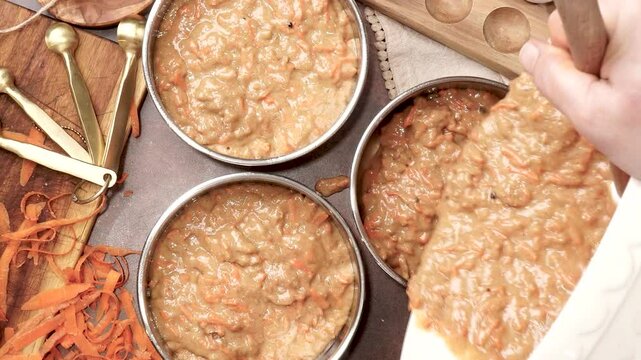Baking a triple layer carrot cake with cream cheese icing.  A perfect spring time cake made with fresh carrots. Cake decorating with cream cheese frosting.  Homemade cake for a family gathering.