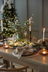 Christmas celebration. Festive table setting with dishware, glasses and decor in room